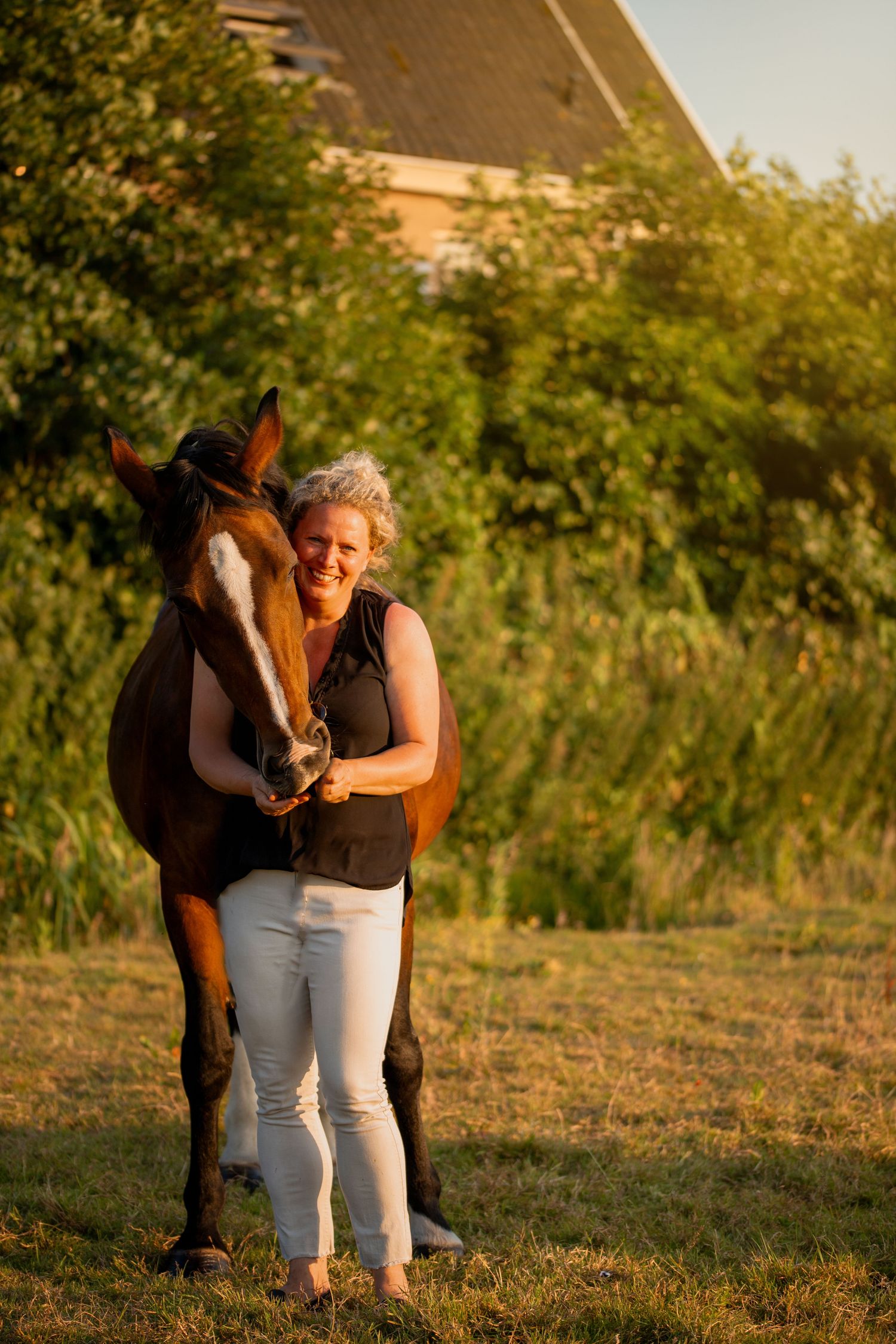 vrouw staat op de foto met haar paard en hij eet uit haar hand