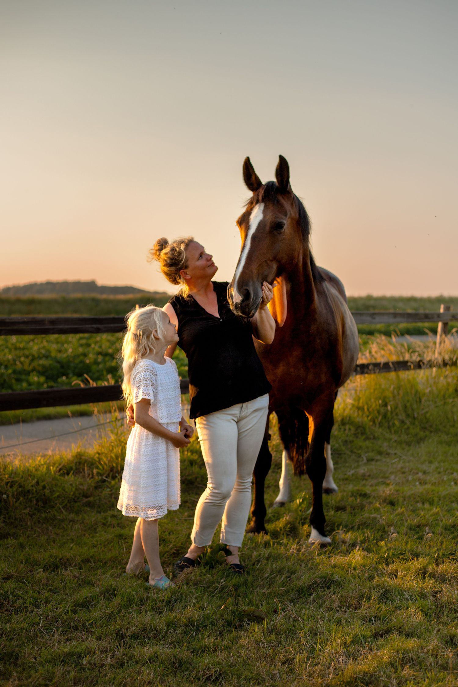 een bruin paard met een blonde vrouw en een blond meisje / kindje